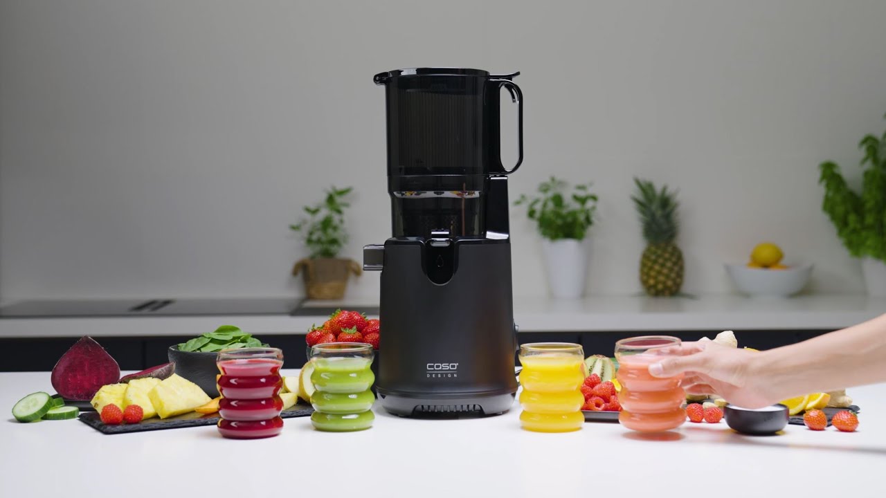 Black juicer with juice glasses and fruits on a white table