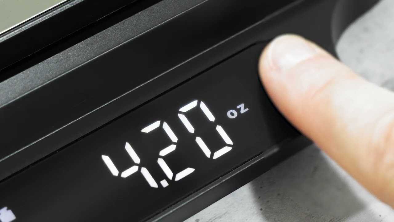 Scale reads 4.20 oz. Finger pressing button. Black background. Digital display.