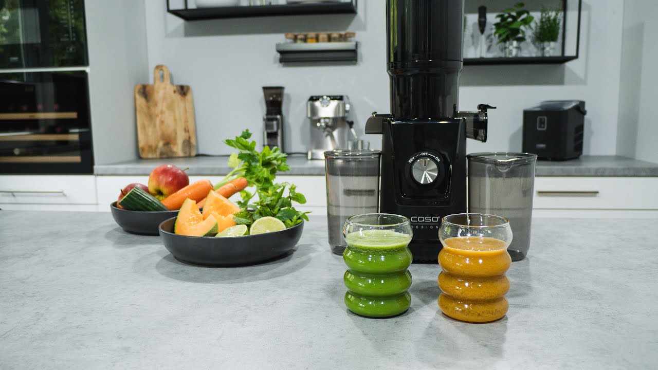 Saftpresse mit Saftgläsern und Obst auf der Theke in der Küche.