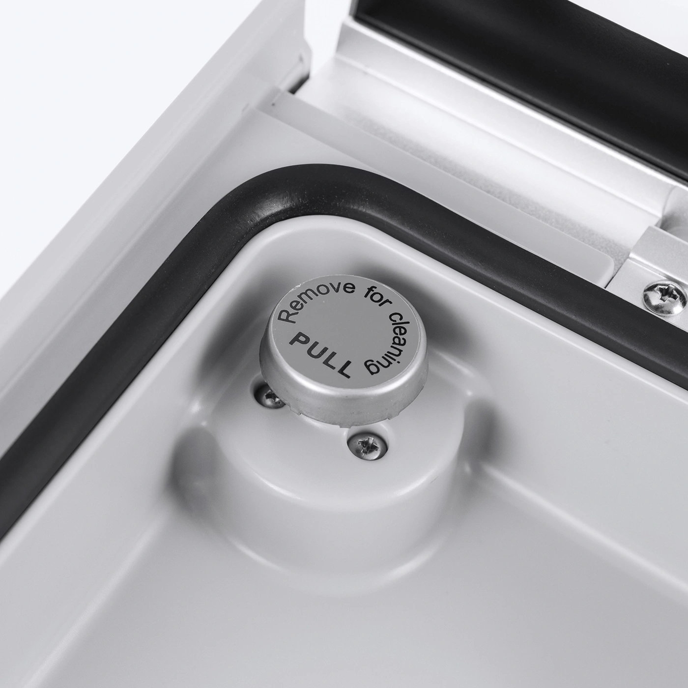 Nahaufnahme eines grauen Knopfes mit der Aufschrift 'Remove for cleaning'