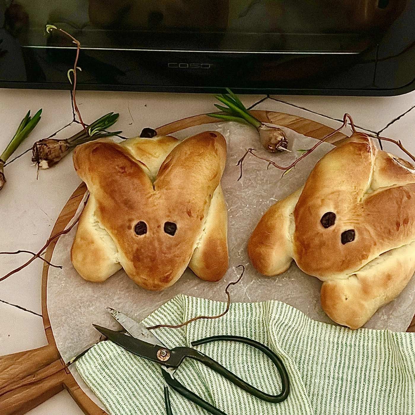 Zwei Hasenbrote auf einem Holzbrett mit Schere und Dekoration.