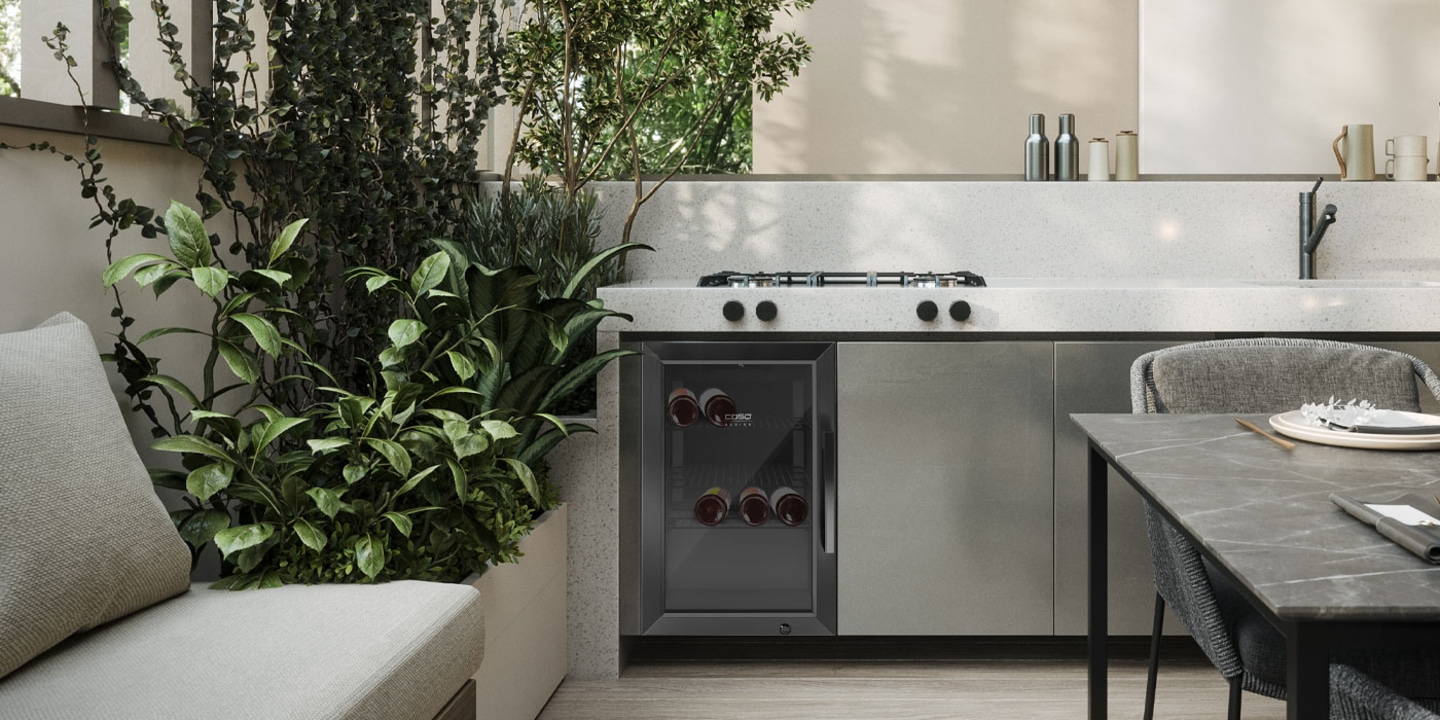 Outdoor kitchen with wine cooler, plants, and dining table in the open air