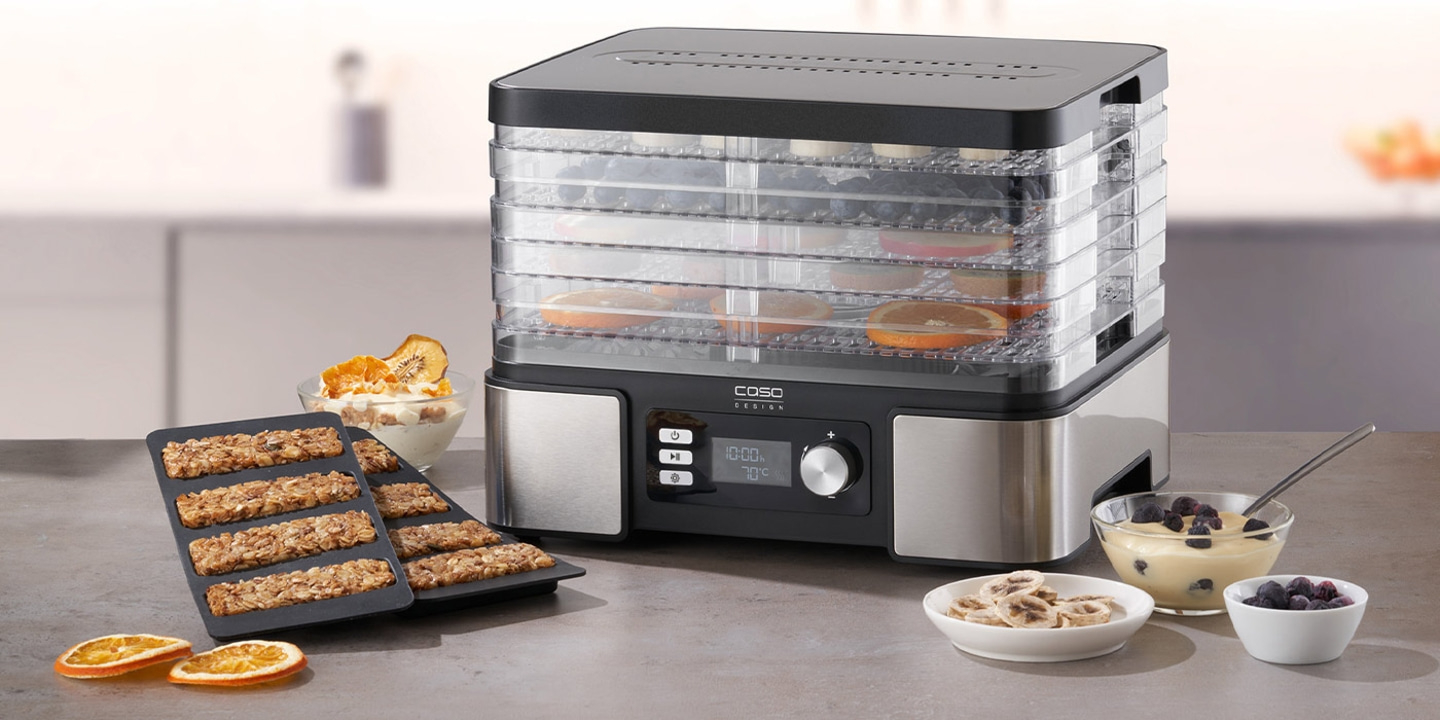 Food dehydrator with dried fruits and snacks on the table in the kitchen