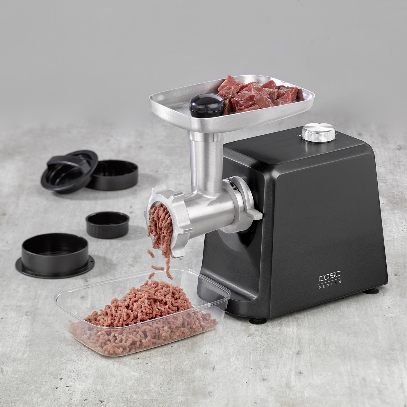 Meat grinder with meat and accessories on gray surface, close-up shot