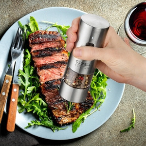 Edles Steak mit Rucola und einer Gewürzmühle, dazu ein Glas Rotwein.