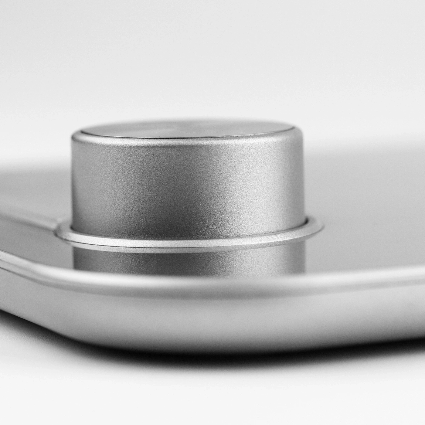 Close-up of a silver round object with a cylindrical top, metallic texture
