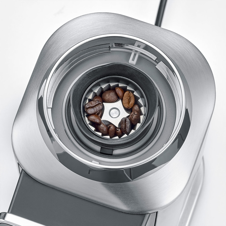 Close-up of coffee beans in a silver coffee grinder burr
