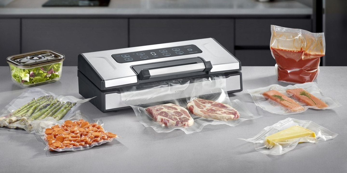 A vacuum sealer with various foods like meat, fish, vegetables, and cheese.