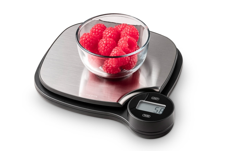 Scale with raspberries in a glass bowl, weighing 58 grams on a white background.