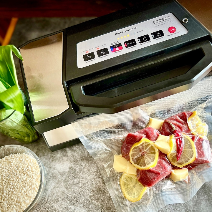 Vacuum sealer with meat, lemons, and cheese in a bag, ready to seal.