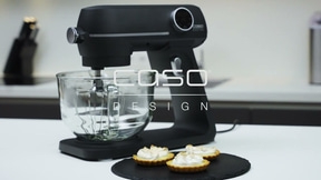 Black mixer with glass bowl and pastries on a black plate