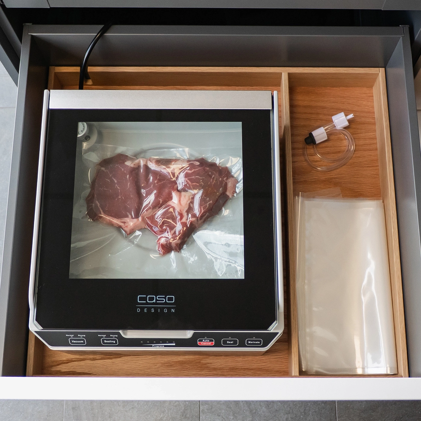 A vacuum sealer with beef, accessories, and bags in a drawer.