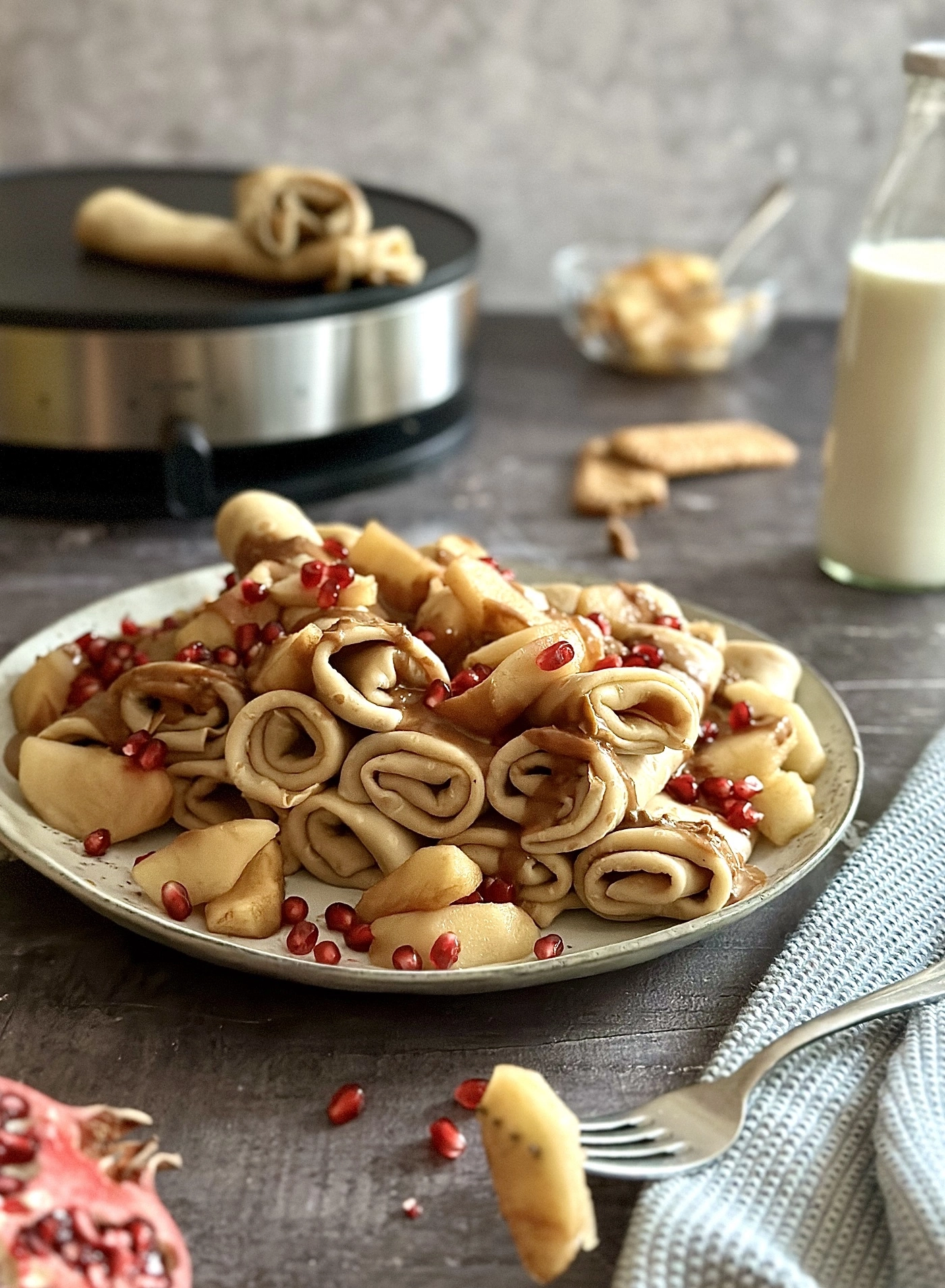 Pfannkuchen mit Äpfeln, Granatapfelkernen und Soße auf einem Teller