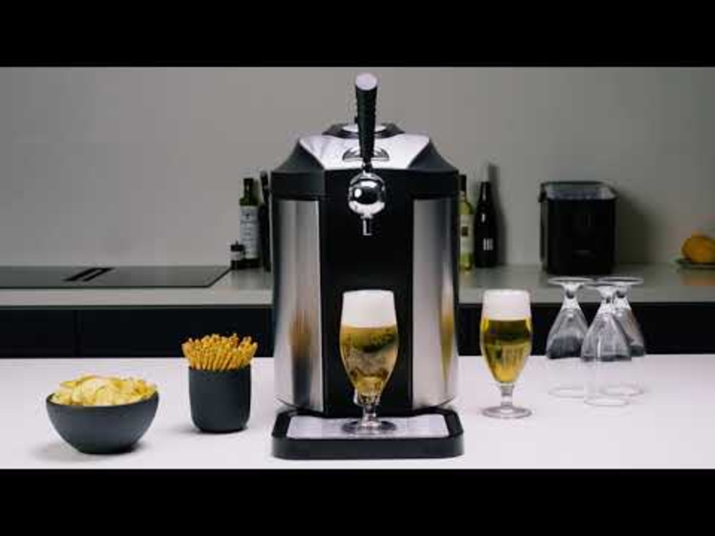 Beer cooler with two glasses, snacks, and glasses on a counter.