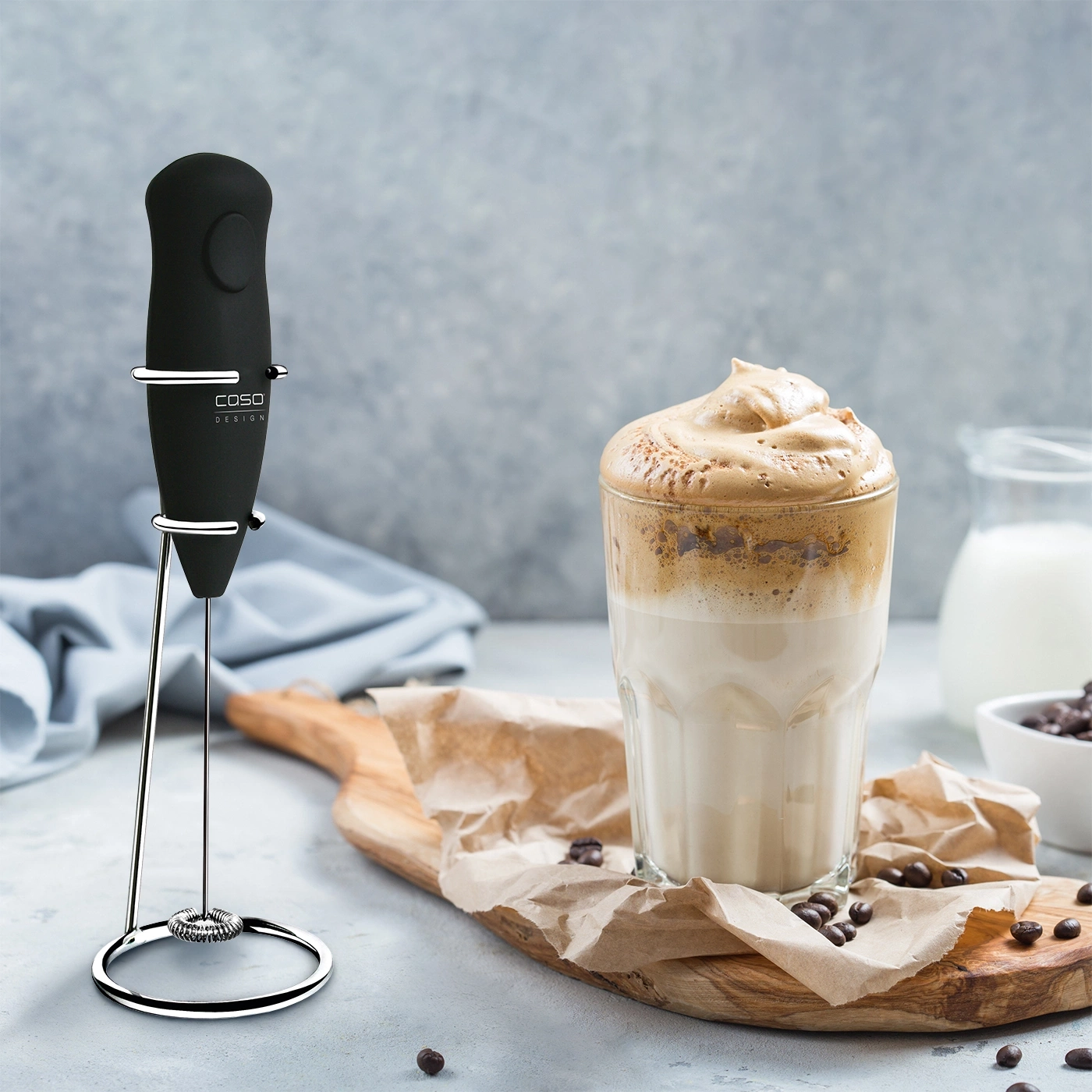 Coffee drink with milk and foam, next to a milk frother.