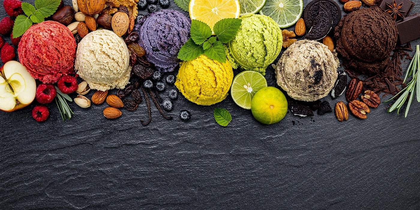 Eiscreme-Auswahl mit Früchten, Nüssen und Schokolade auf dunklem Untergrund