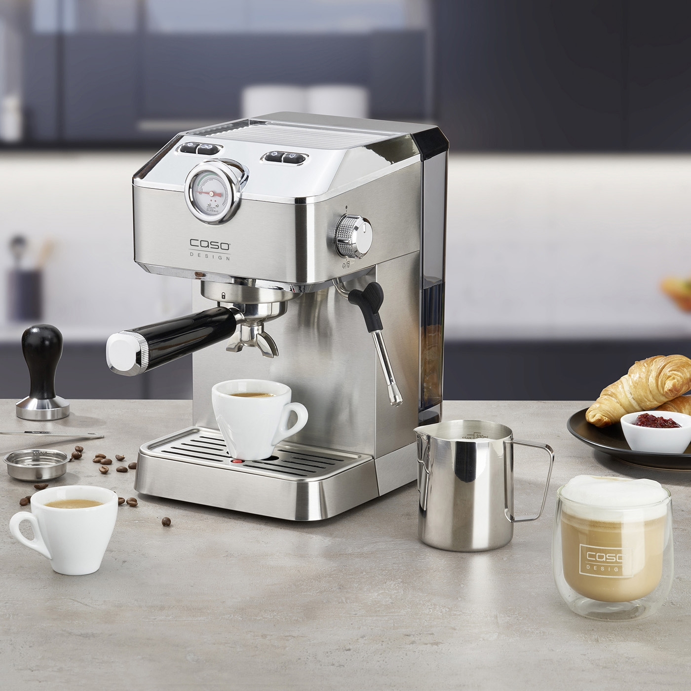 Espresso machine with accessories, coffee, and pastries on a table