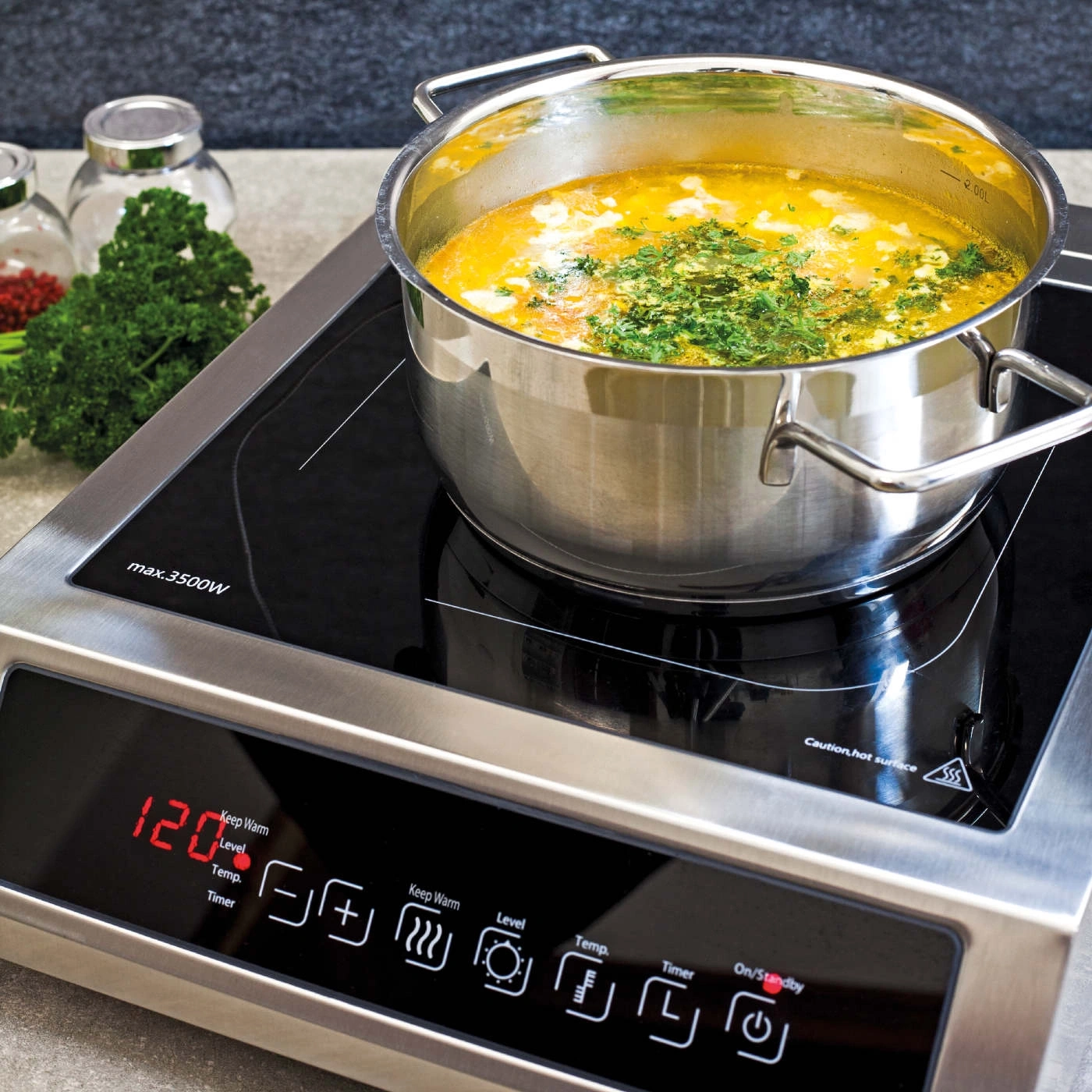 Topf mit Suppe auf Induktionskochfeld. Kochfeld mit Bedienfeld und Anzeige.