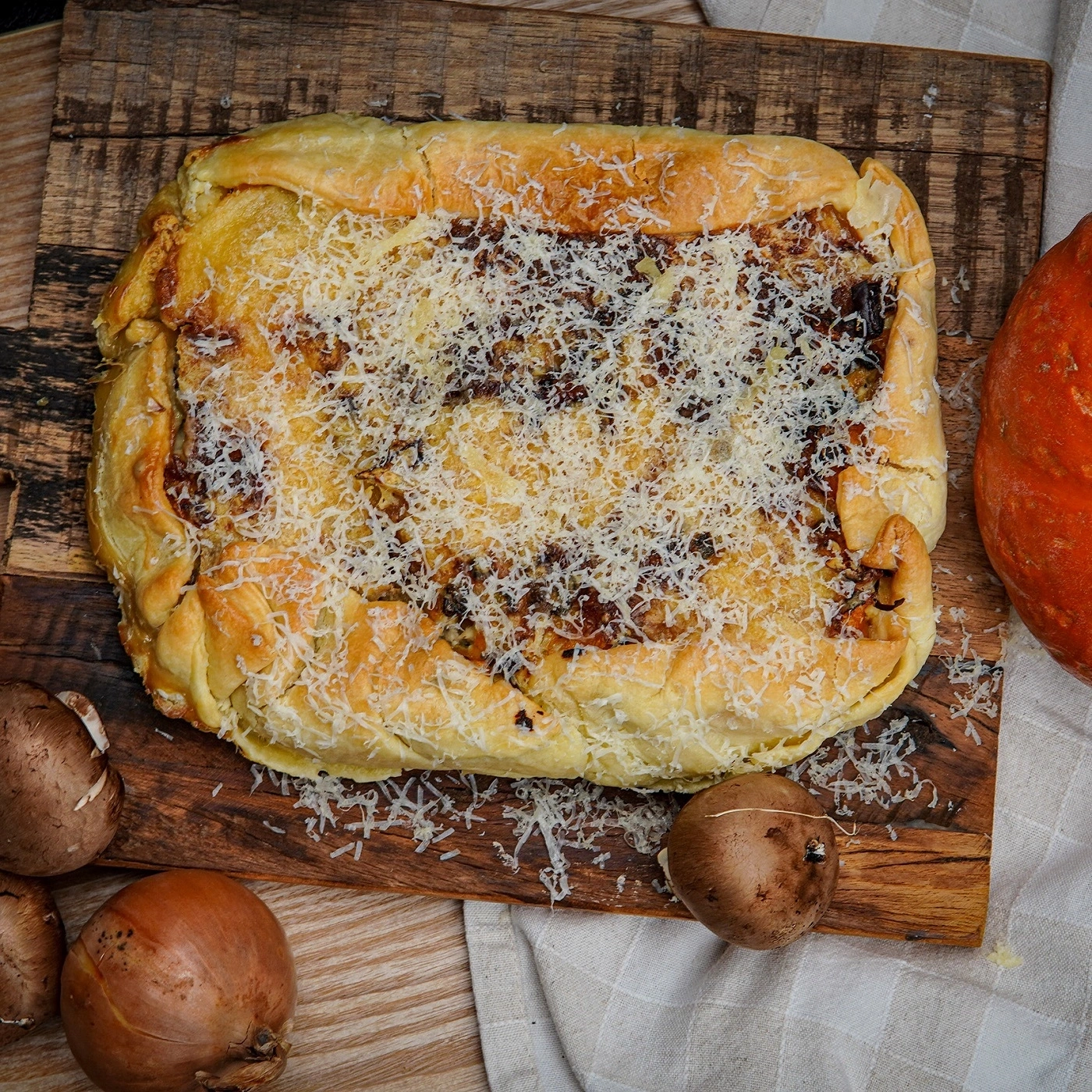 A savory pie with mushrooms, onions, and cheese on a wooden board.