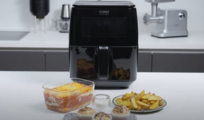 Schwarze Fritteuse mit Essen, Lasagne, Pommes und Muffins auf dem Tisch.