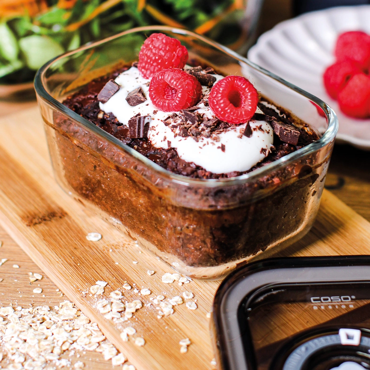 Dessert mit Himbeeren und Sahne in einem Glas auf einem Holzbrett