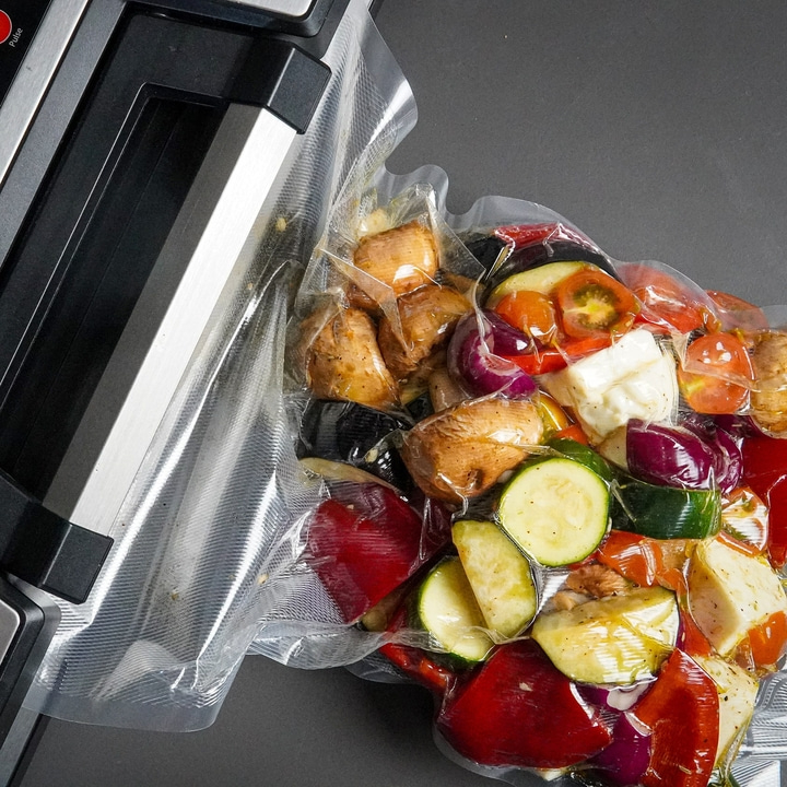 Vakuumverpacktes Fleisch mit Kräutern und Gewürzen auf schwarzem Untergrund.