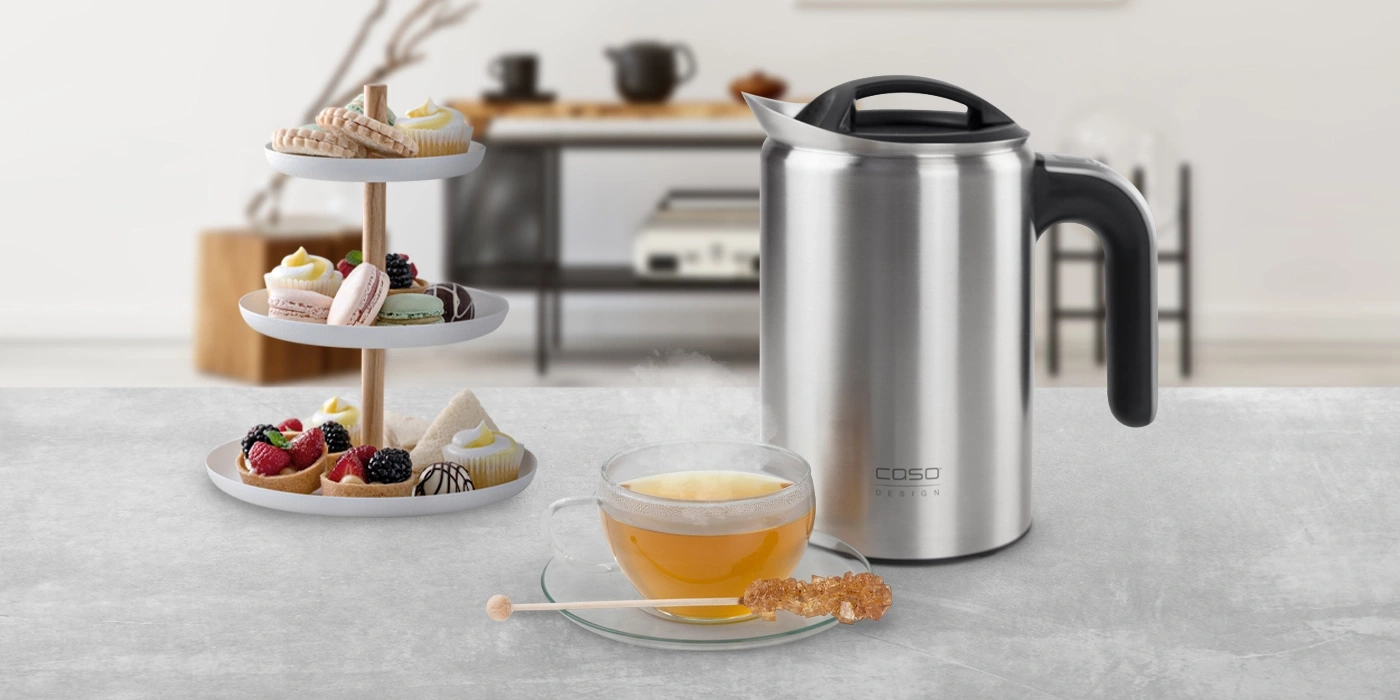 Stainless steel teapot with pastries and tea on a table