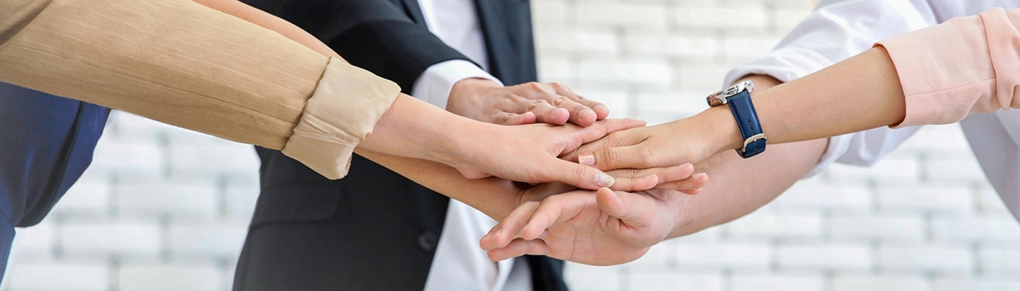 Teamwork-Konzept: Hände aufeinander, um Einheit und Zusammenarbeit zu symbolisieren.