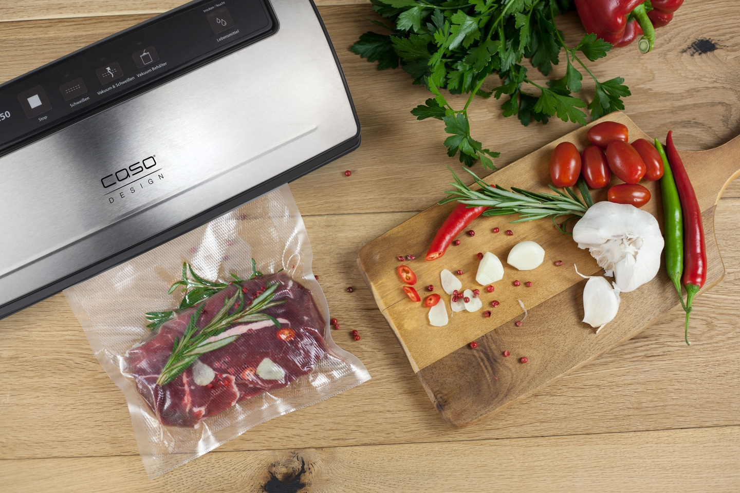 Vakuumierer mit Fleisch, Kräutern und Gemüse auf Holztisch