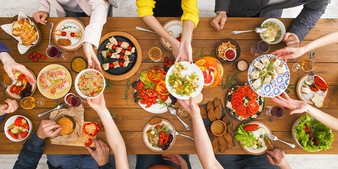Ein Tisch voller Essen, Hände reichen Gerichte, gemeinsames Essen, Mahlzeit, Freunde, Familie