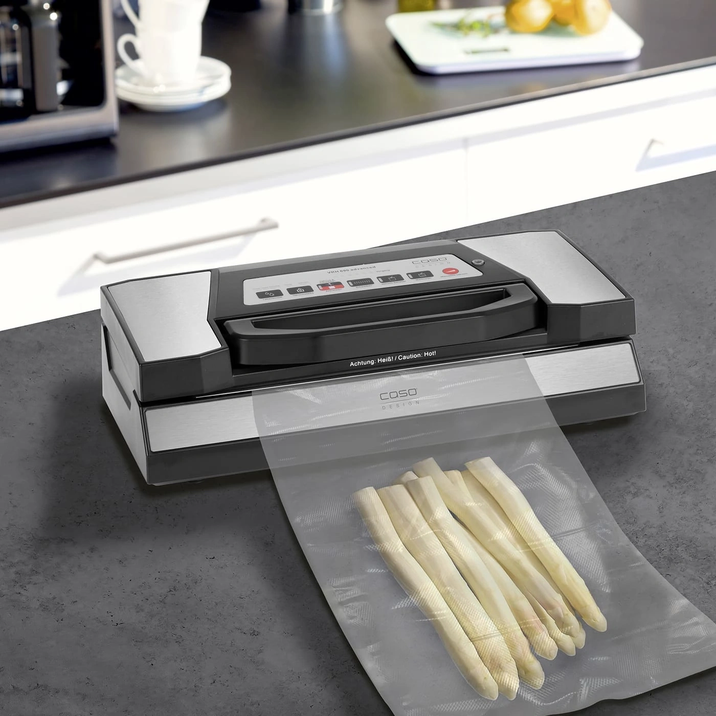 Vakuumiergerät mit Spargel in einer Tüte auf einer Arbeitsplatte in der Küche.