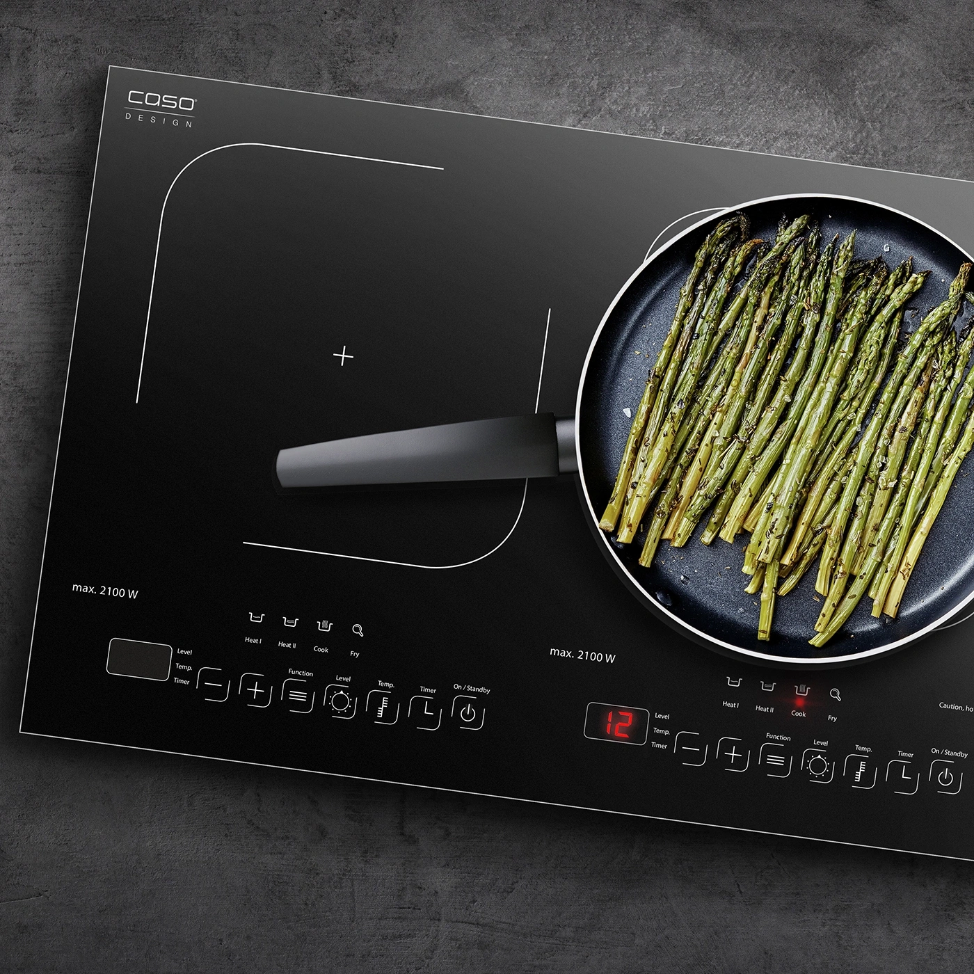 Schwarzes Kochfeld mit Spargel in der Pfanne, Bedienfeld mit Knöpfen und Anzeige.