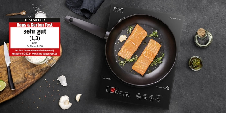 Induction hob with salmon in pan, rated very good by Haus & Garten Test.