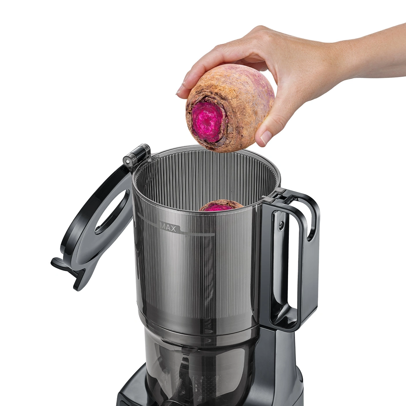 Hand placing beet into juicer. Processing vegetables for juice.