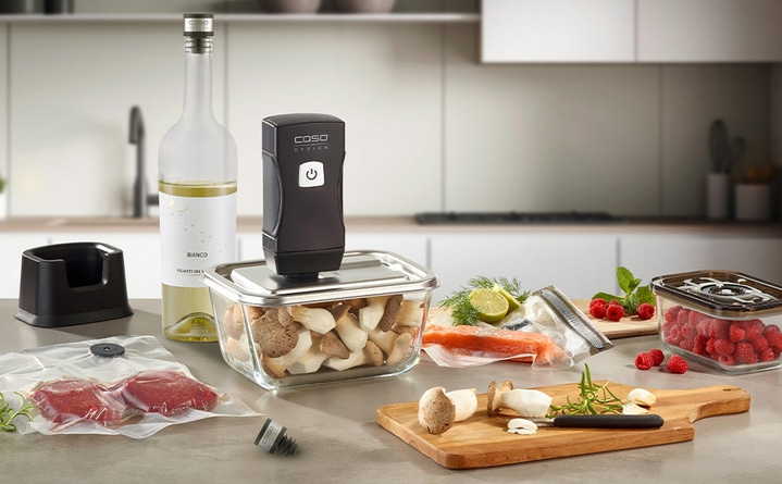 Kitchen scene with food, vacuum sealer, and wine. Fresh ingredients.