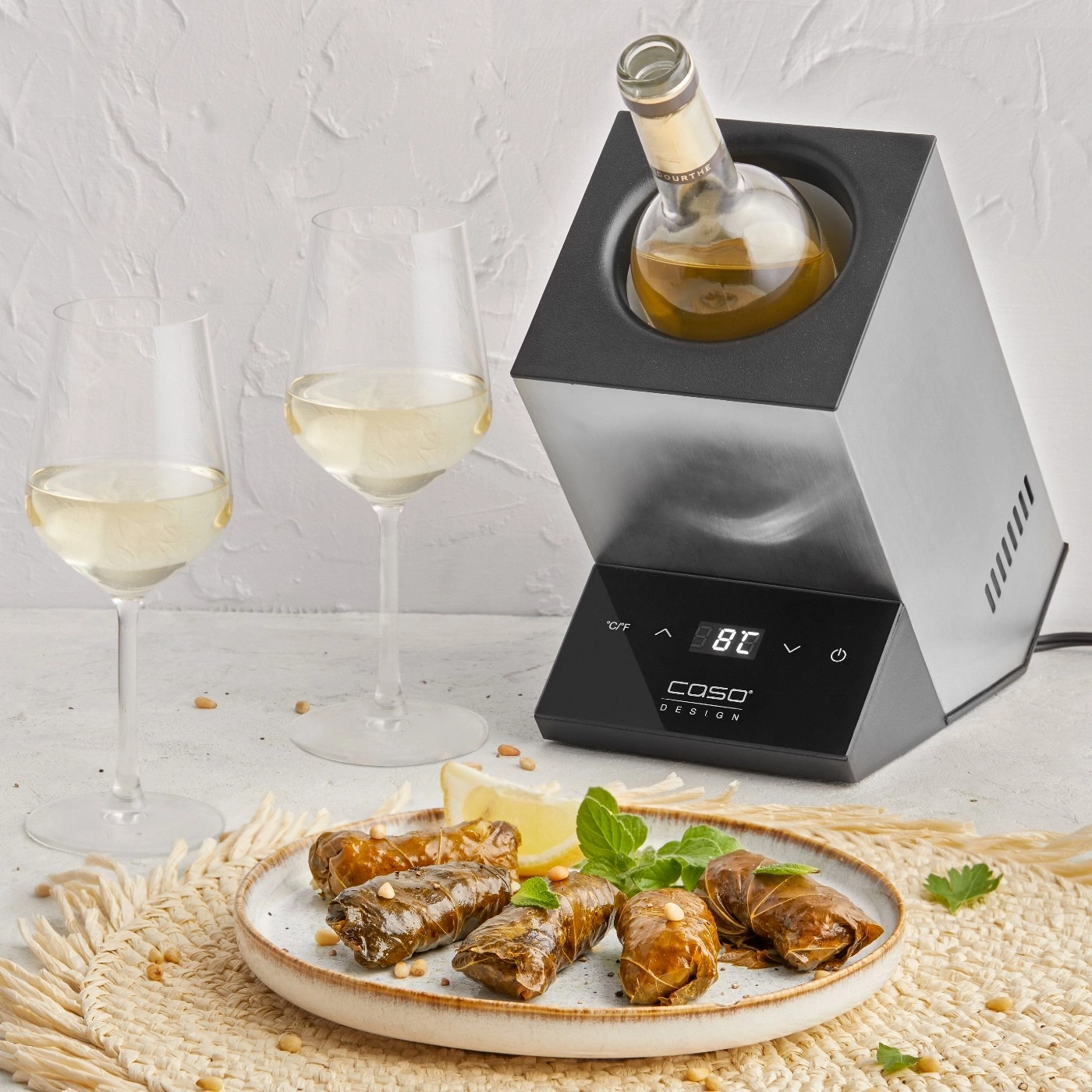 Wine glasses, wine, wine cooler, stuffed grape leaves, lemon, mint, placemat.
