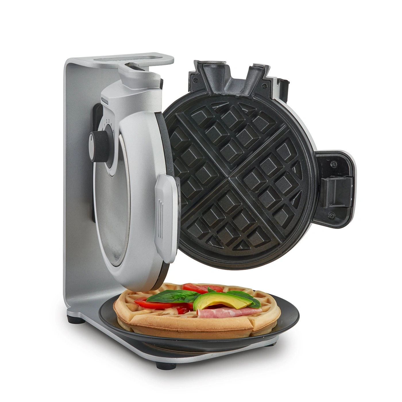 Waffeleisen mit Waffel, belegt mit Tomaten, Avocado und Schinken auf einem Teller.