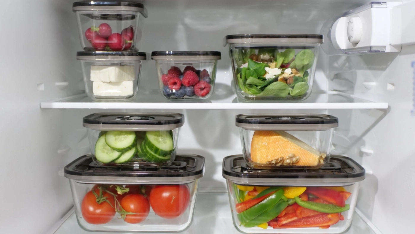 Refrigerator with various foods in glass containers, neatly organized and stored.