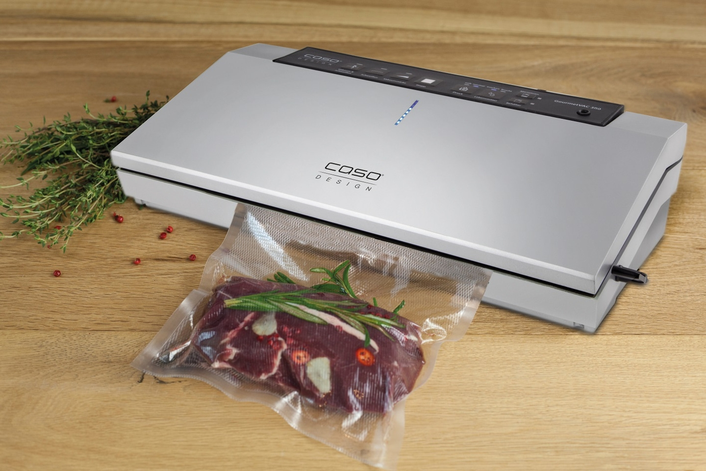 Vakuumiergerät mit Fleisch in einer Tüte auf einem Holztisch