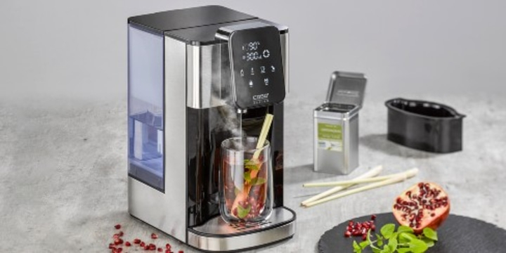Kettle with glass, tea, pomegranate and herbs on a table