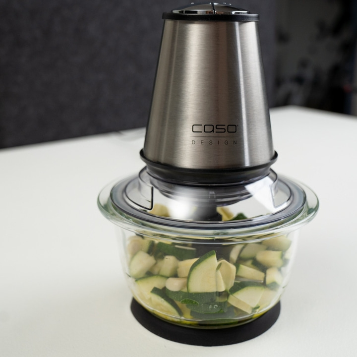 Electric food chopper with vegetables on white table, Caso Design.
