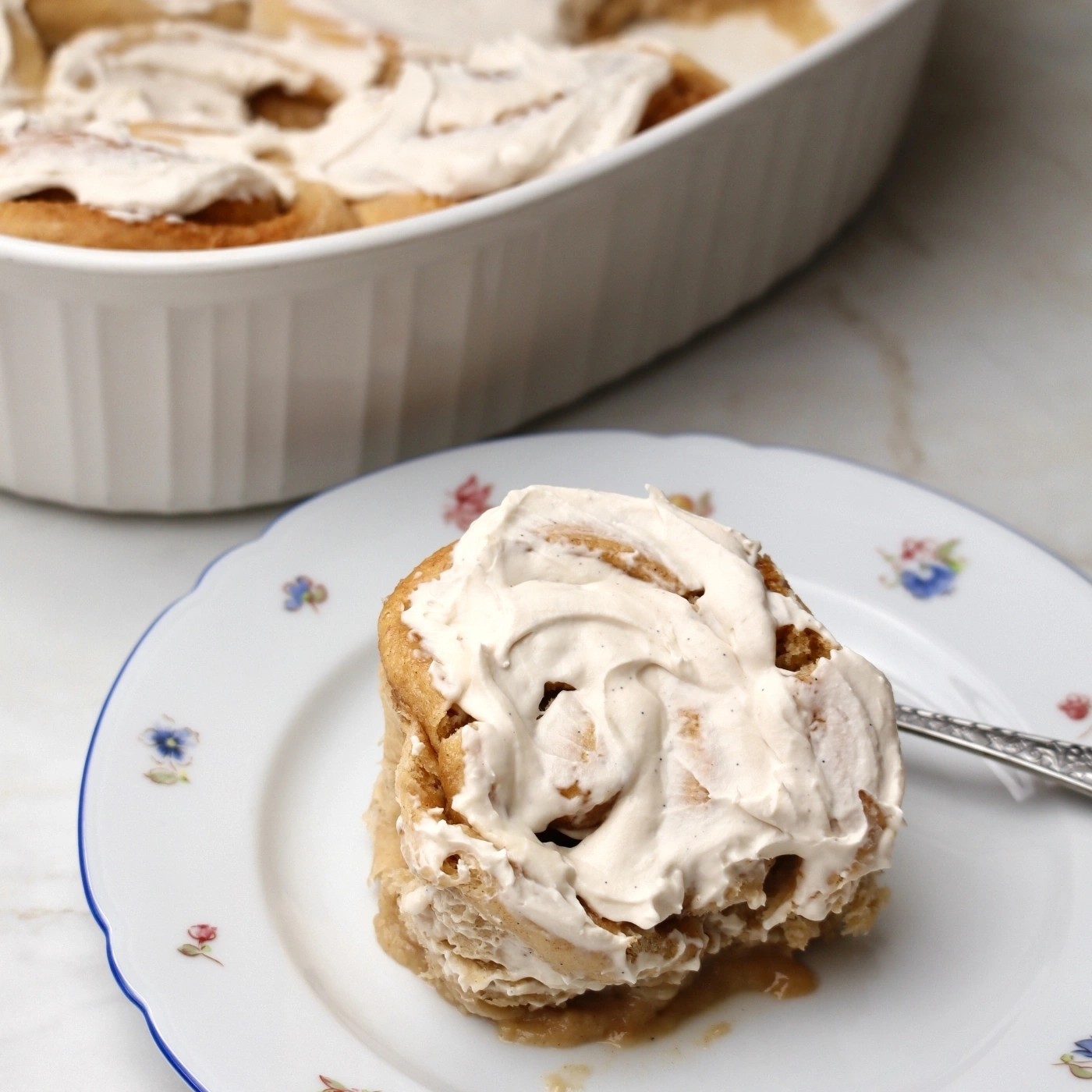 A single cinnamon roll with frosting on a plate.