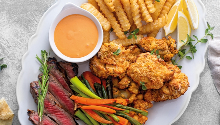 Plate with steak, chicken, fries, vegetables and sauce