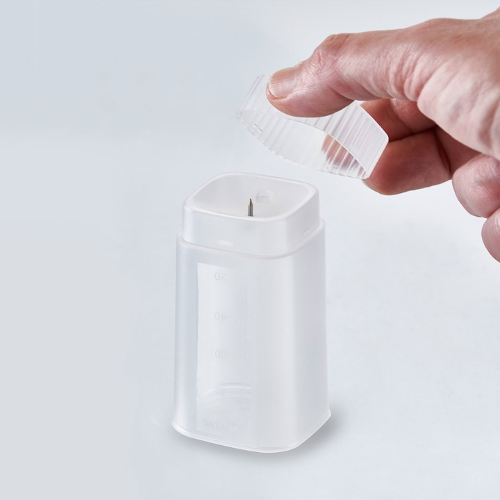 Container with lid and hand. Measuring scale. White background. Close-up shot.