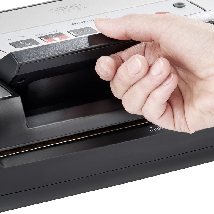 Hand drückt Knopf auf Vakuumiergerät. Caso Design VRH 590 adv. Feucht, trocken.
