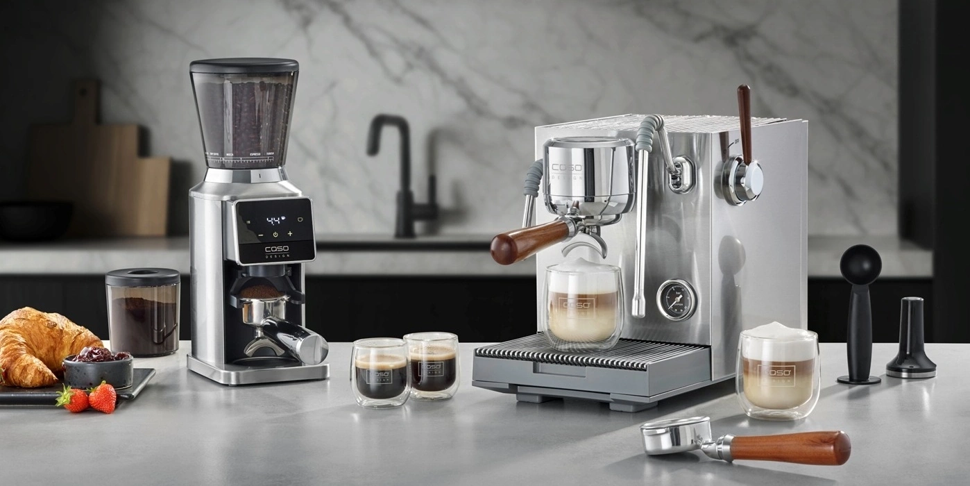 Kaffeemaschine mit Zubehör und Gebäck auf einer Arbeitsplatte