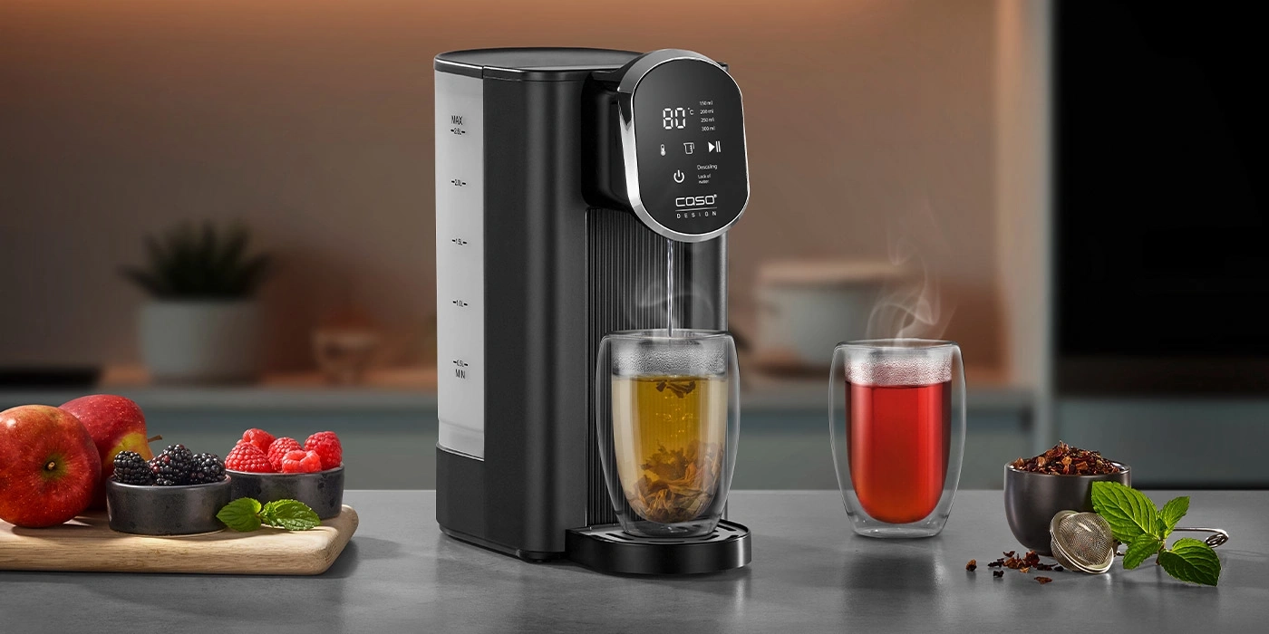 A water dispenser with two glasses of tea and fruits beside it.