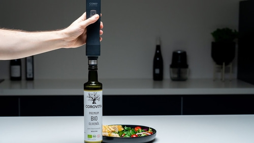Person hält Olivenölflasche mit Salat in der Nähe