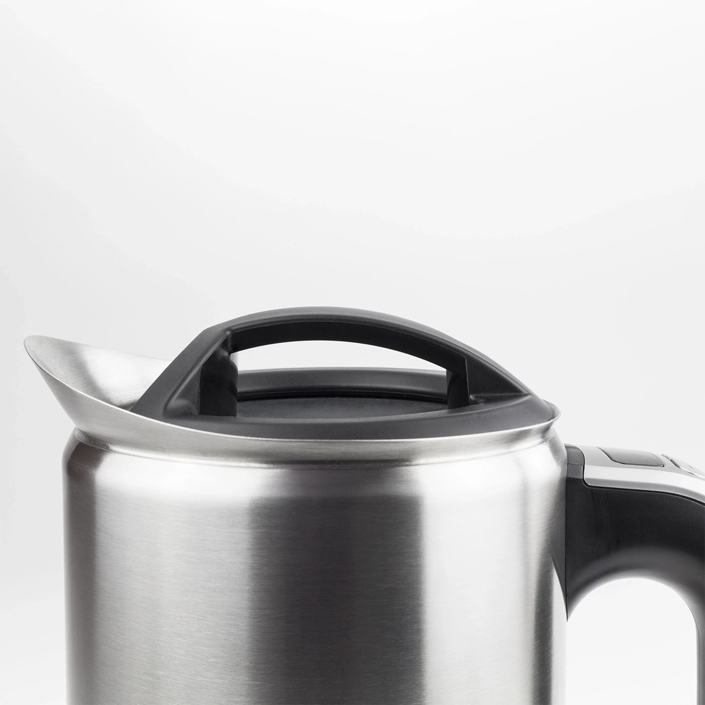Close-up of a silver kettle with a black handle and lid against a white background.