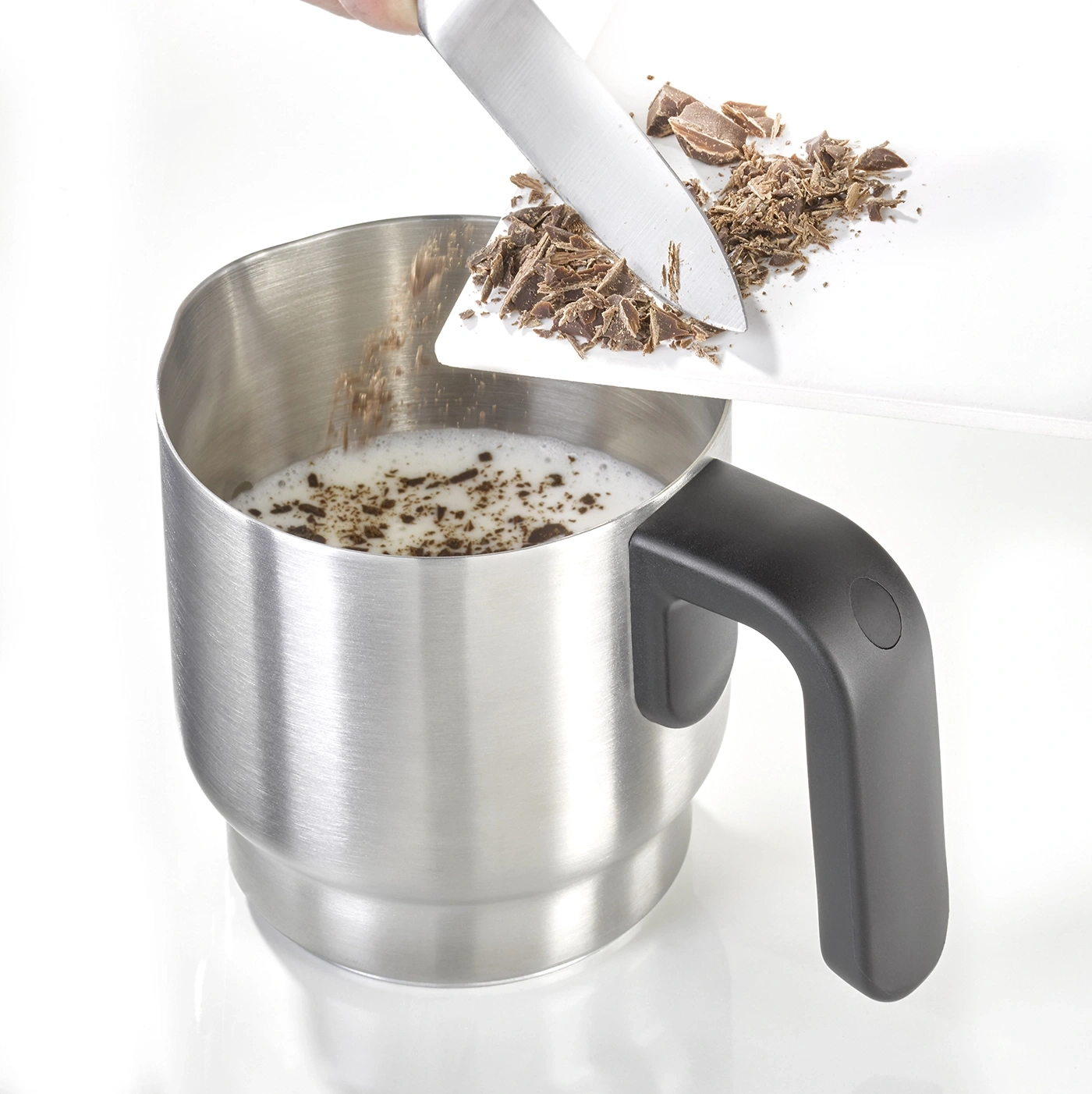 Schokolade wird in eine Tasse mit Milch gegeben, um ein Getränk zuzubereiten.